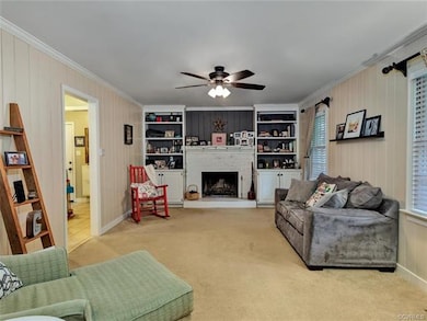 Family room has wood burning fireplace with brick hearth, built in bookcases, and ceiling fan.