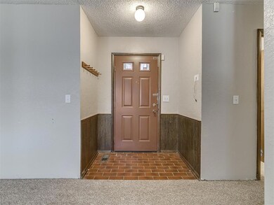 Foyer with wooden walls, dark colored carpet, and 