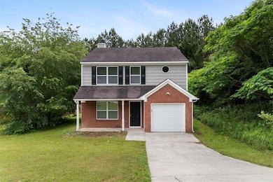 View of front of property with a chimney, brick siding, a front yard, and driveway