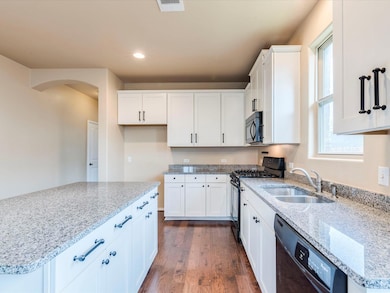 Kitchen with black appliances, arched walkways, d