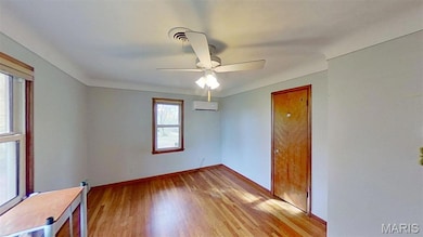 Unfurnished room featuring light wood-type flooring, a ceiling fan, and a wall mounted air conditioner