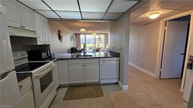 Kitchen with white appliances, sink, light tile pa