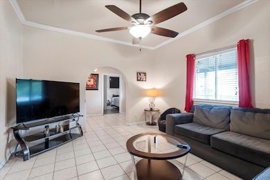 Living area featuring crown molding, light tile p