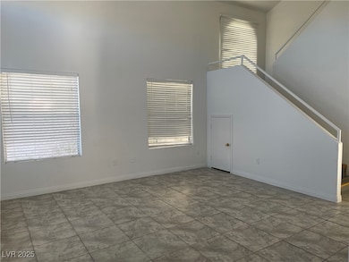 Unfurnished living room featuring stairs, baseboar