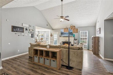 Living room with ceiling fan, plenty of natural light, dark wood-type flooring, a fireplace, and a textured ceiling