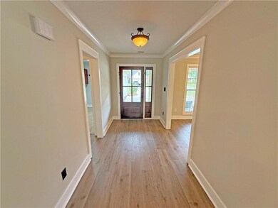 Doorway to outside with light wood-style floors and ornamental molding