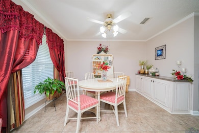 Dining area with a ceiling fan, ornamental molding, baseboards, and light tile patterned floors