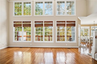 Unfurnished living room featuring light wood finished floors, a high ceiling, and a chandelier