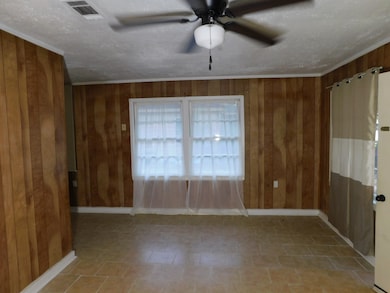 Unfurnished room with wooden walls, ceiling fan, and a textured ceiling