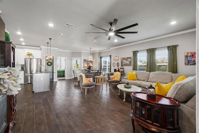 Living room featuring a textured ceiling, crown molding, dark wood-type flooring, plenty of natural light, and a chandelier
