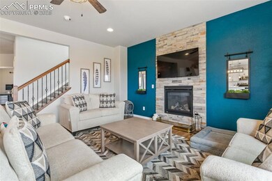 Living room featuring a fireplace, wood finished floors, stairs, and ceiling fan