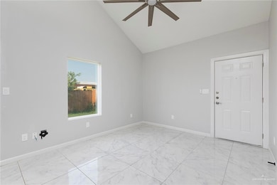 Empty room with ceiling fan, light marble finish floors, baseboards, and high vaulted ceiling