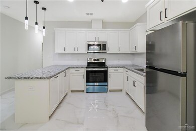 Kitchen featuring white cabinetry, kitchen peninsula, light tile floors, and stainless steel appliances