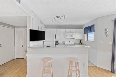 Kitchen with white appliances, light wood-style floors, white cabinets, and light countertops