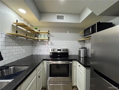 Kitchen featuring stainless steel appliances, white cabinetry, sink, and decorative backsplash