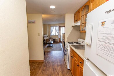 Kitchen featuring white appliances and dark hardwo