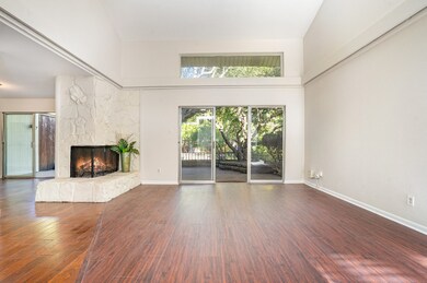 Living room featuring a stone fireplace, a towering ceiling, and dark wood-style flooring
