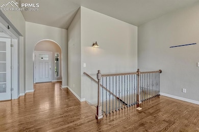 A beautifully designed hallway boasts stunning wood floors and an elegant upstairs landing.