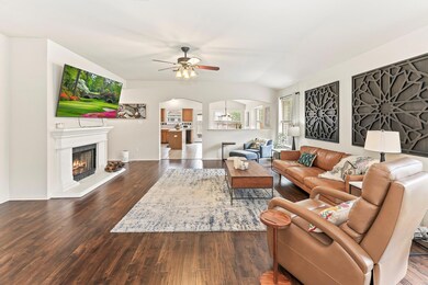 Living room with ceiling fan, a lit fireplace, ar