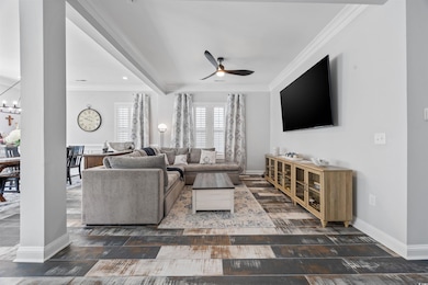 Living area featuring a ceiling fan, crown molding, wood finished floors, and a chandelier