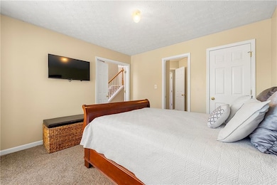 Bedroom featuring light colored carpet, baseboards, and a textured ceiling
