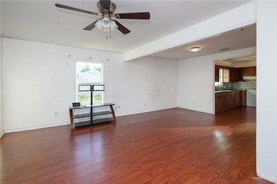 Empty room featuring a ceiling fan, baseboards, and dark wood-style flooring