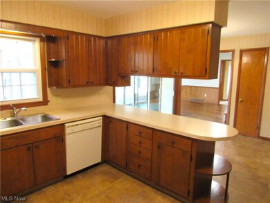 Kitchen with sink, light tile floors, white dishwasher, and kitchen peninsula