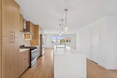 Kitchen featuring appliances with stainless steel finishes, a kitchen island with sink, decorative light fixtures, recessed lighting, and light stone countertops