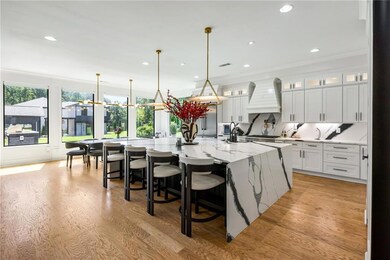 Kitchen featuring glass insert cabinets, a breakfast bar, light wood finished floors, light stone counters, and white cabinetry