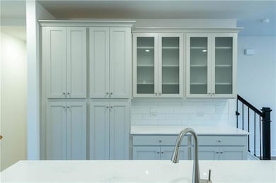 Kitchen with glass insert cabinets, light stone counters, and decorative backsplash