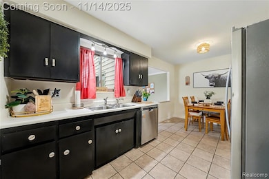Kitchen with dark cabinetry, appliances with stainless steel finishes, light countertops, and light tile patterned flooring