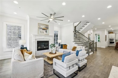 Living area with ornamental molding, stairs, a fireplace, baseboards, and recessed lighting