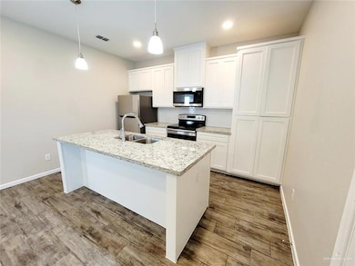 Kitchen with light hardwood / wood-style flooring, tasteful backsplash, a kitchen island with sink, stainless steel appliances, and sink