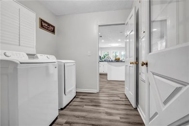Laundry area with light wood-style floors, a textured ceiling, and washing machine and clothes dryer