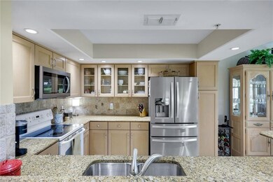 Kitchen with stainless steel appliances, light stone countertops, glass insert cabinets, recessed lighting, and backsplash