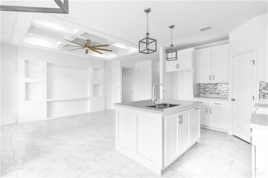 Kitchen with white cabinets, a kitchen island with sink, pendant lighting, sink, and ceiling fan