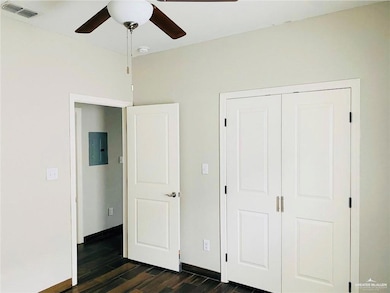 Unfurnished bedroom featuring dark wood finished floors, a closet, electric panel, and ceiling fan