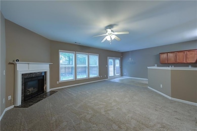 Unfurnished living room featuring a ceiling fan, a premium fireplace, carpet, and baseboards