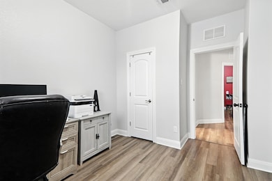 Office area with light wood-style flooring and ba