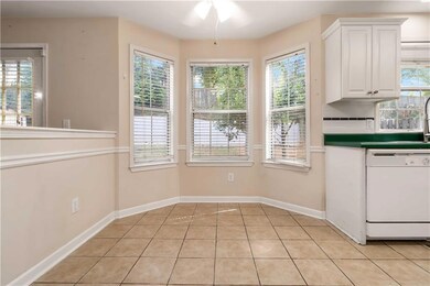 Kitchen with white dishwasher, light tile patterned floors, white cabinetry, ceiling fan, and dark countertops