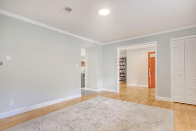 Empty room featuring ornamental molding, light wood-style flooring, and baseboards