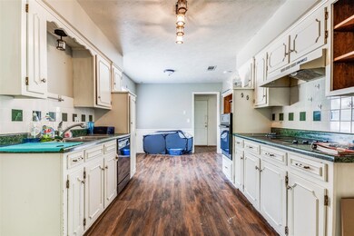 Kitchen featuring white cabinets, black appliances, dark hardwood / wood-style floors, backsplash, and sink