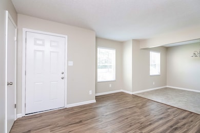 Foyer with wood finished floors, a textured ceiling, and baseboards
