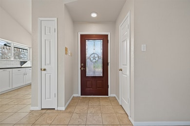 The entryway features a beautiful glass front door with a Texas star design, welcoming you into a bright interior accented by neutral tones and tile flooring.