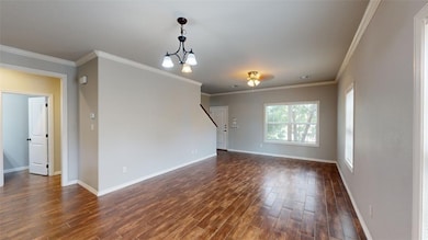 Unfurnished living room with crown molding, a chandelier, and dark wood-style floors