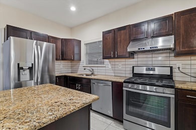 Kitchen featuring under cabinet range hood, a sink