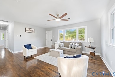 Living area featuring attic access, dark wood-style floors, and ceiling fan
