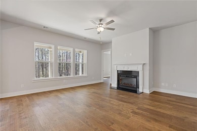 Unfurnished living room with a glass covered fireplace, wood finished floors, and ceiling fan