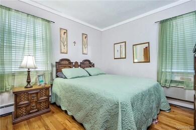 Bedroom with crown molding, wood finished floors, and baseboard heating