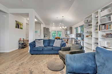 Living room featuring a chandelier, light wood-style flooring, baseboards, and vaulted ceiling